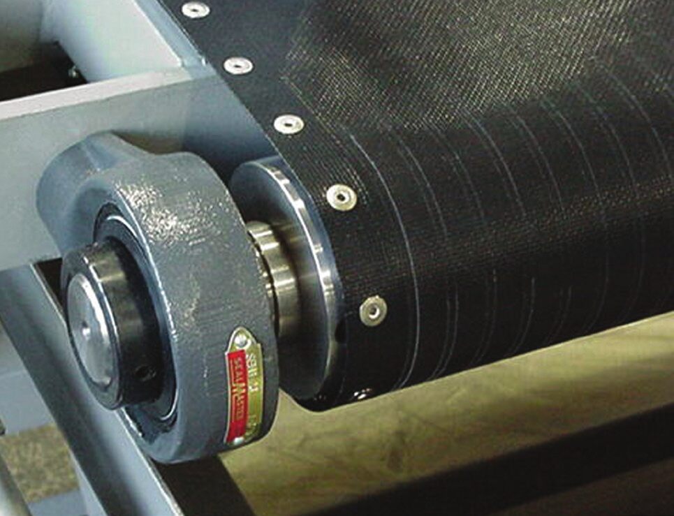 Close-up of the magnetic roll on an Eriez rare earth roll separator with the black Kevlar feed belt wrapped over it and the roll bearing alongside