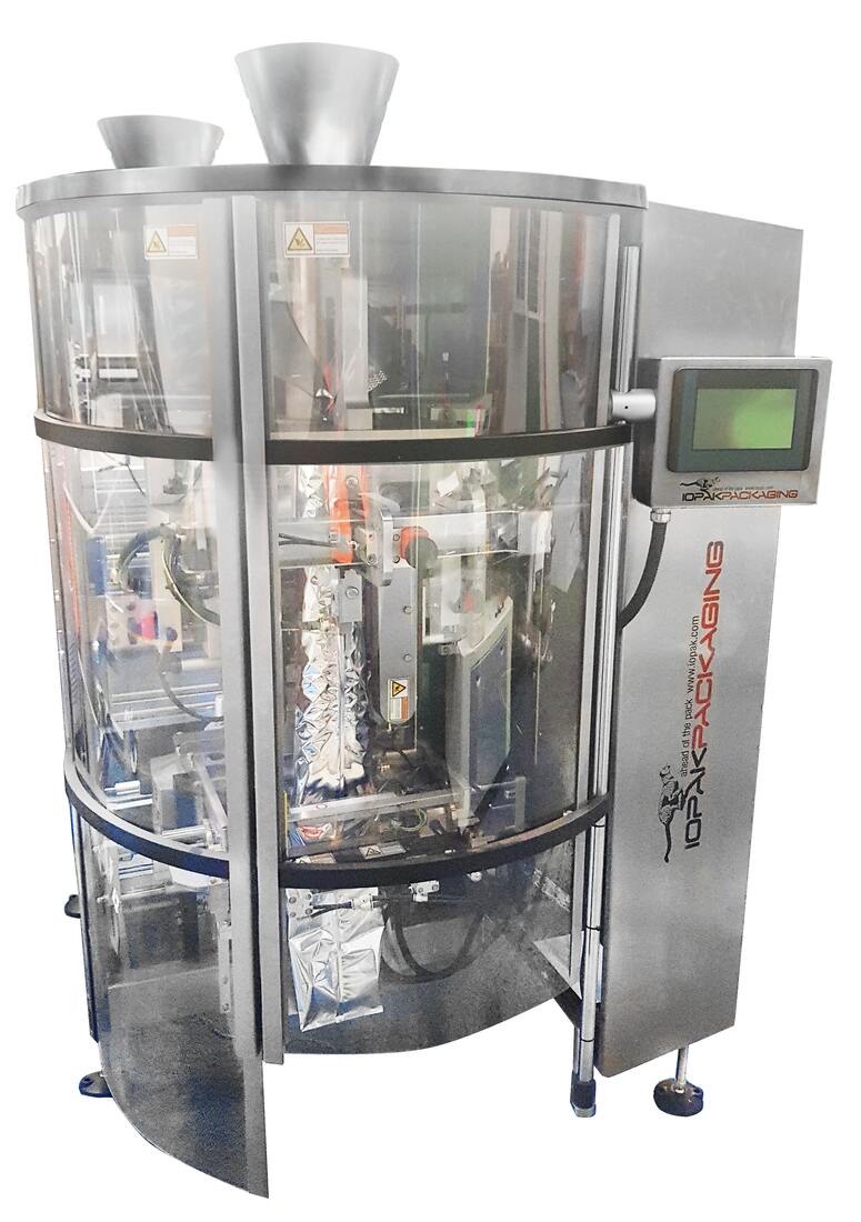 IOPAK BS-2520 continuous motion vertical form fill seal bagger with twin infeed chutes above the curved guard doors, the forming tube and cross seal jaws behind them and the retractable control panel on the right, IOPAK PACKAGING badge on the frame