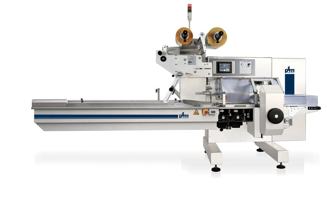 PFM Falcon horizontal flow wrapper with film reels above the forming box and a long product infeed conveyor