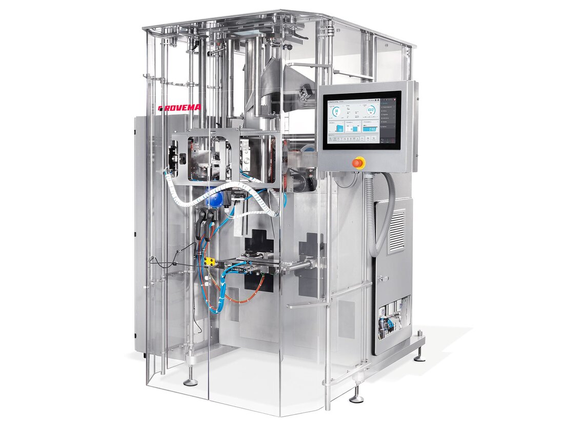 Rovema BVC continuous motion vertical form fill seal bagger behind its clear guard doors, forming tube and cross seal jaws visible with the control screen on the side